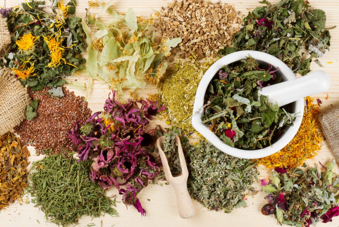 A selection of herbs with a pestle and mortar for blending